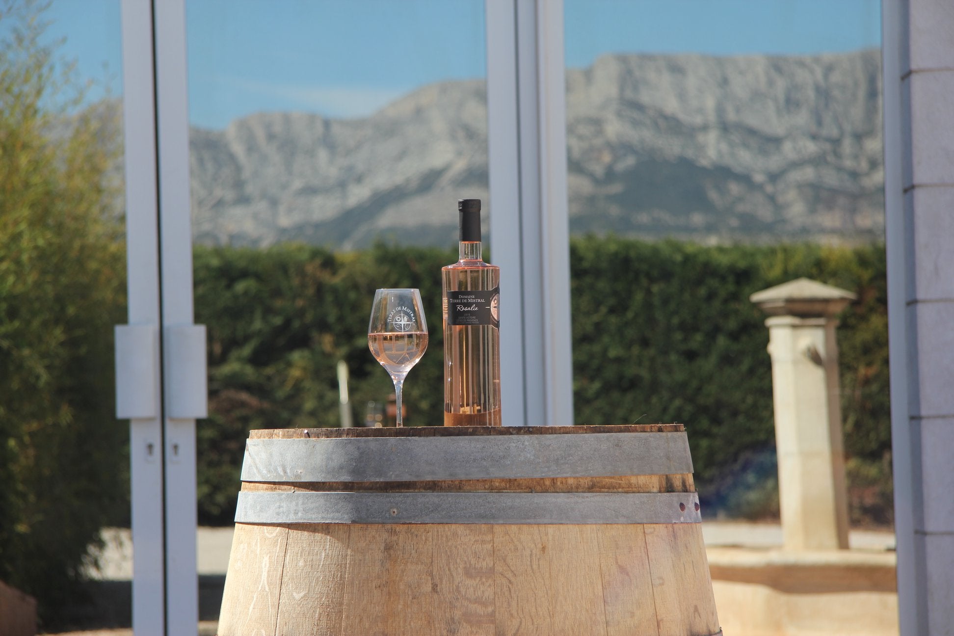 Rose Wine bottle and glass on a wooden barrel with mountains in the background